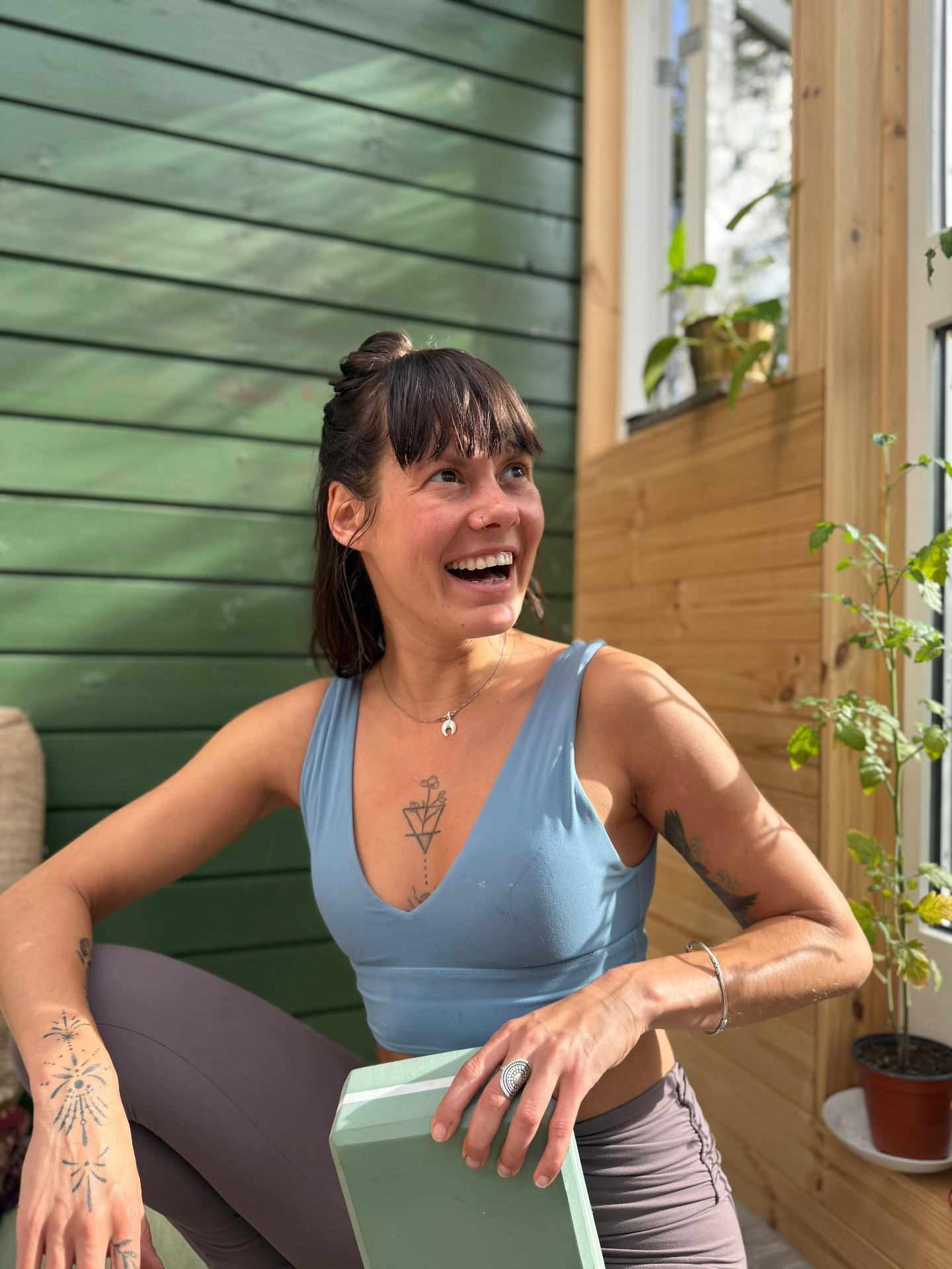 Airi, somatic practitioner, sitting on a porch with yoga blocks